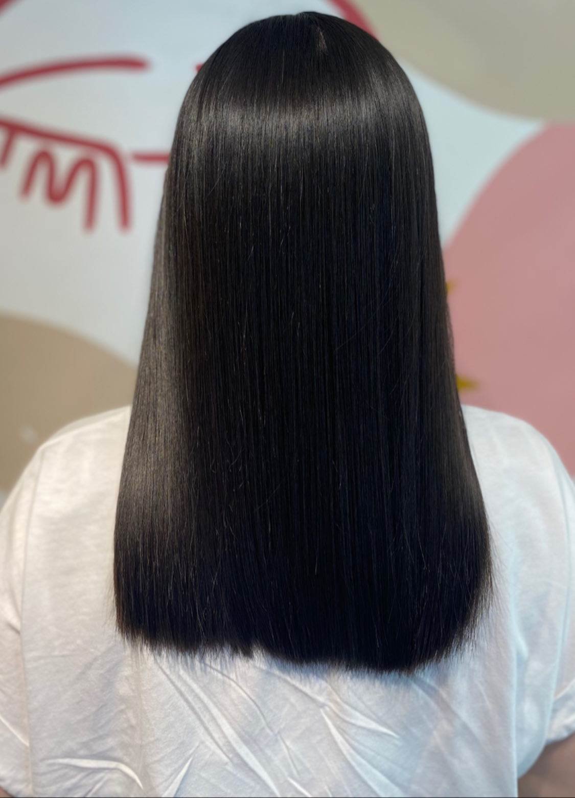 Cabello negro liso y brillante después de la reposición de aminoácidos en The Beauty Bar